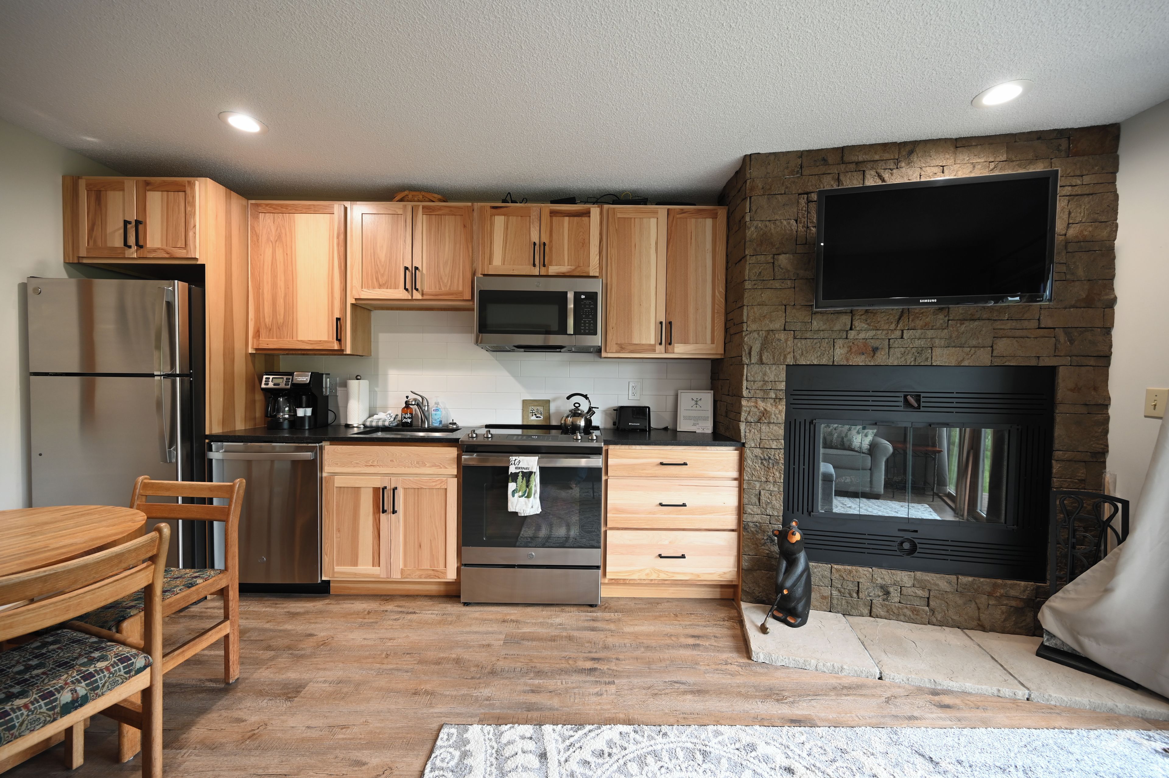 Una cocina moderna con armarios de madera, electrodomésticos de acero inoxidable, un microondas integrado y una chimenea de piedra.