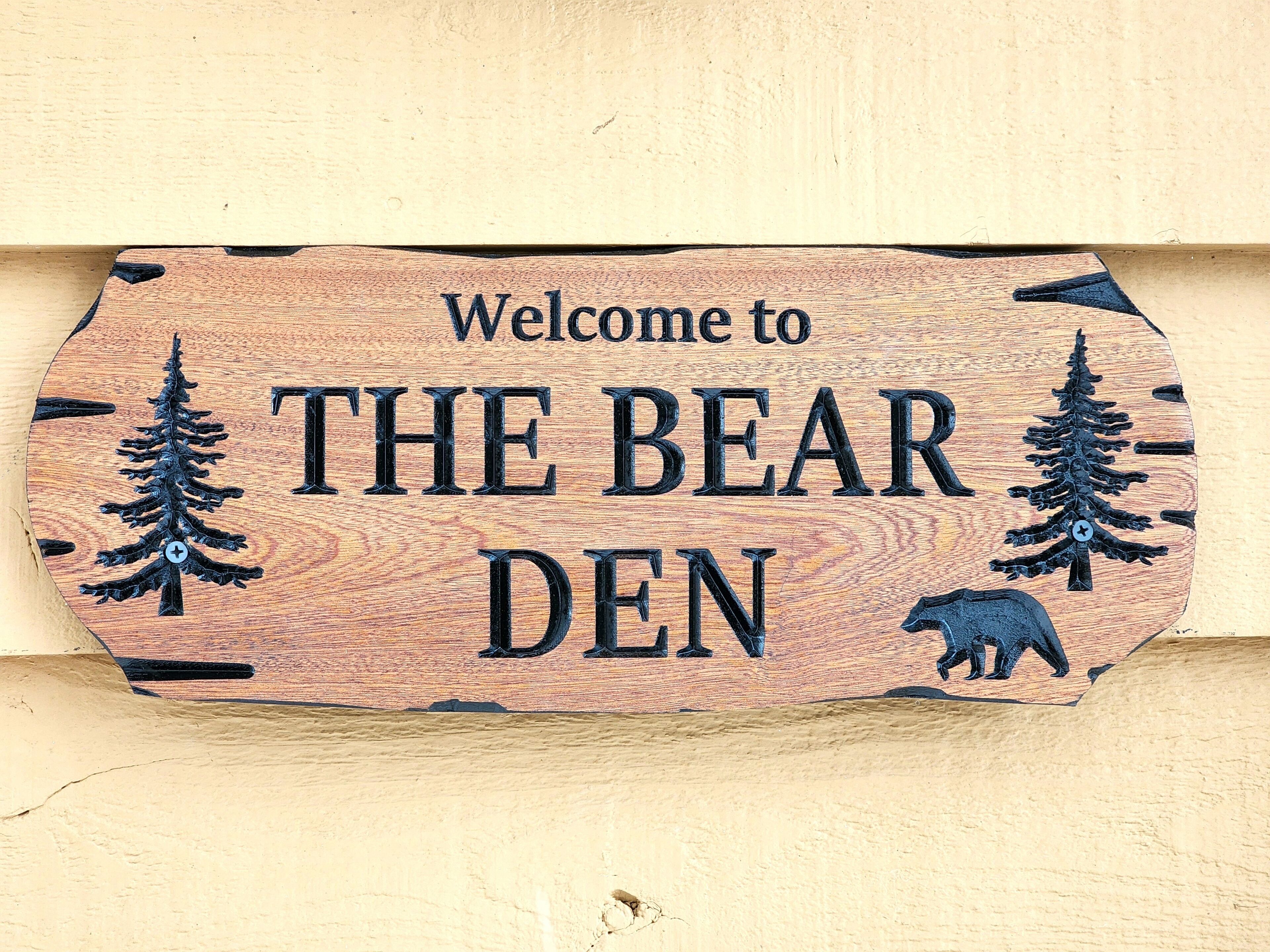 A wooden sign with the text "Welcome to THE BEAR DEN" and two bear illustrations.
