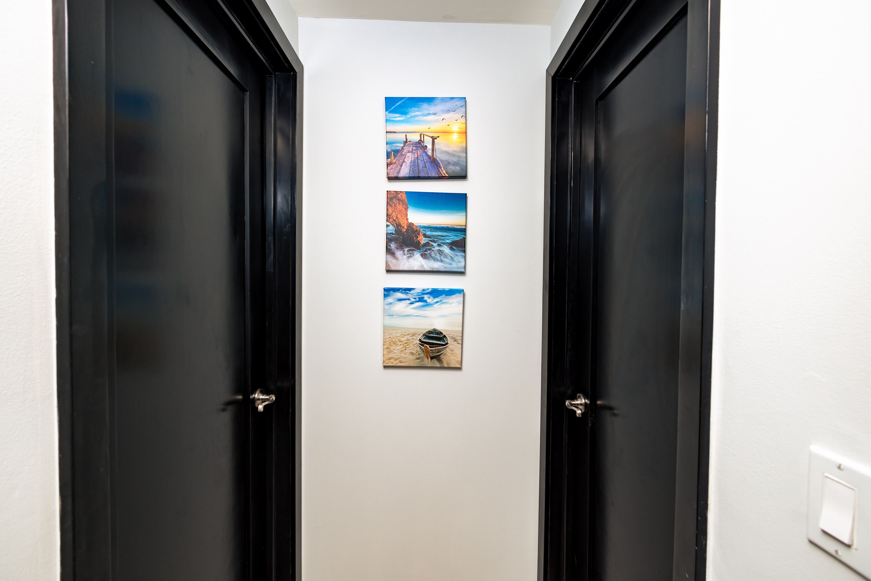 Een gang met drie ingekaderde foto's aan de muur.