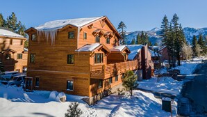 Een houten lodge met meerdere balkons en uitzicht op besneeuwde bergen.