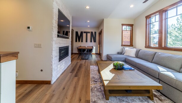 Een moderne woonkamer met een stenen openhaard, een groot raam en een plafondventilator.