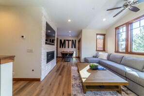 Een moderne woonkamer met een stenen openhaard, een groot raam en een plafondventilator.