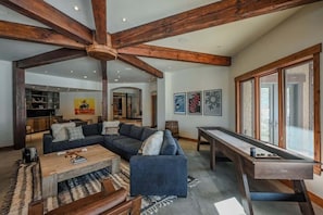 A spacious living area with a large sofa, coffee table, and a pool table.