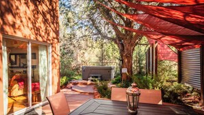Un espace patio aménagé avec une table et des chaises, un jacuzzi et un coin salon couvert avec un auvent rouge.