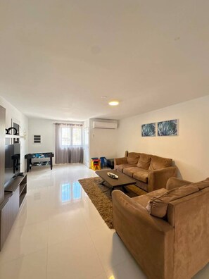 A modern living room with a sofa, a coffee table, and a TV.