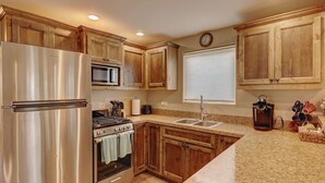 Una cucina con mobili in legno, elettrodomestici in acciaio inossidabile, un forno a microonde, un lavandino e un piano cottura.