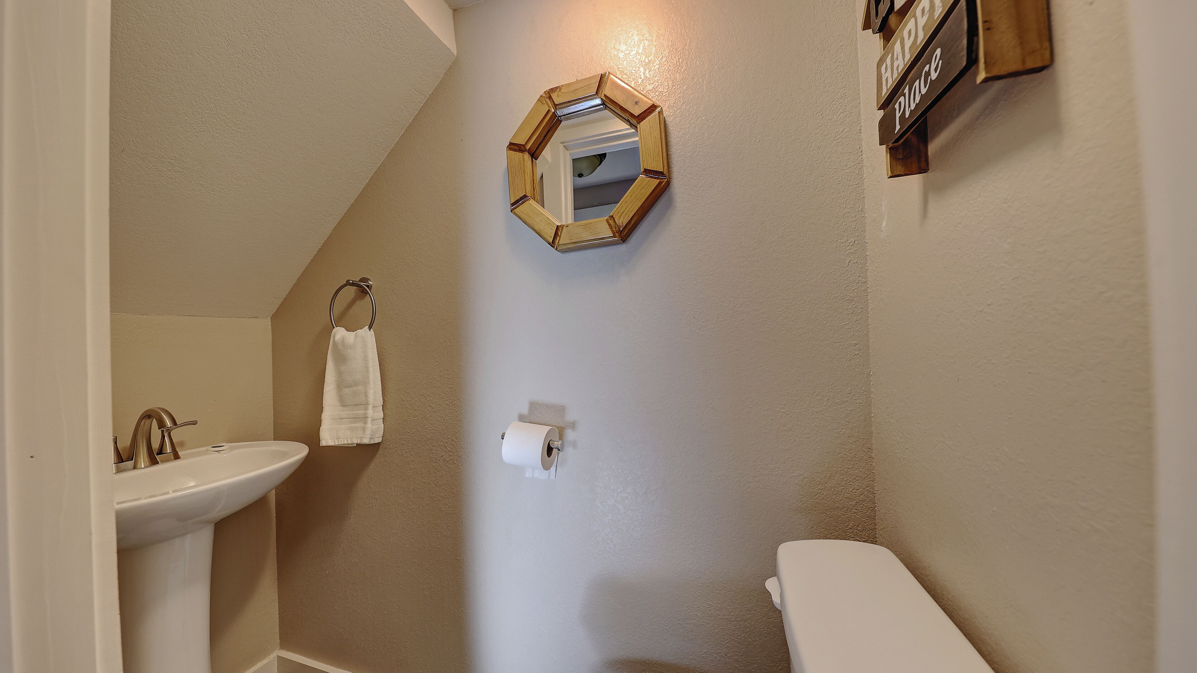 A bathroom with a sink, toilet, and a mirror on the wall.