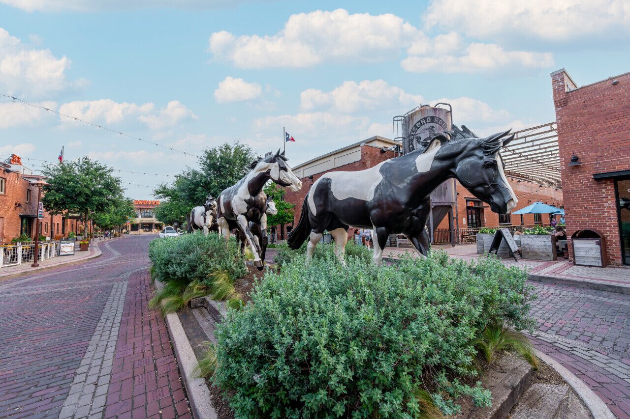 Eine Straße mit großen Pferdestatuen, Backsteingebäuden und blauem Himmel.