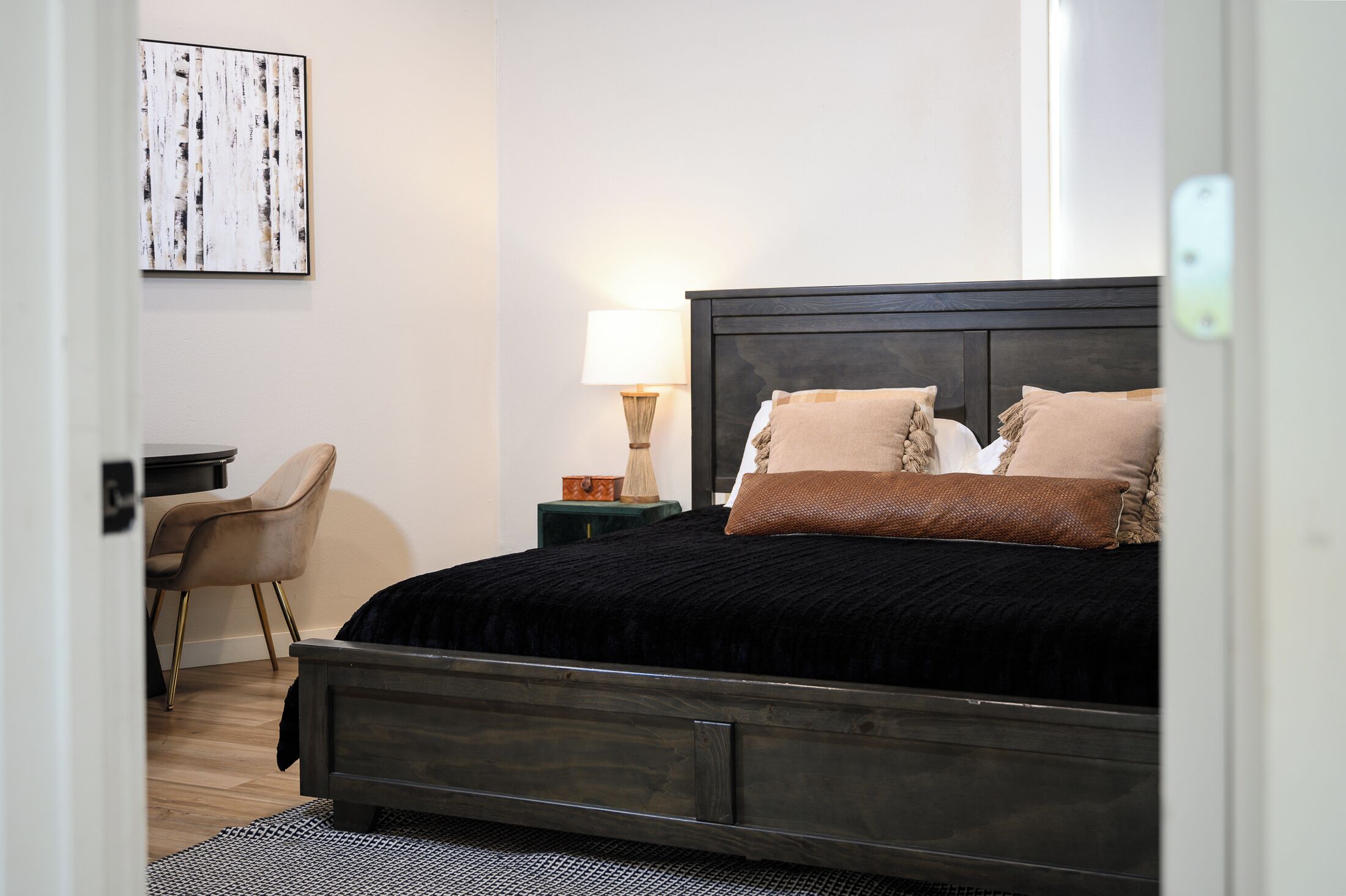 A neatly arranged bedroom with a dark wooden bed, a bedside lamp, and a chair.