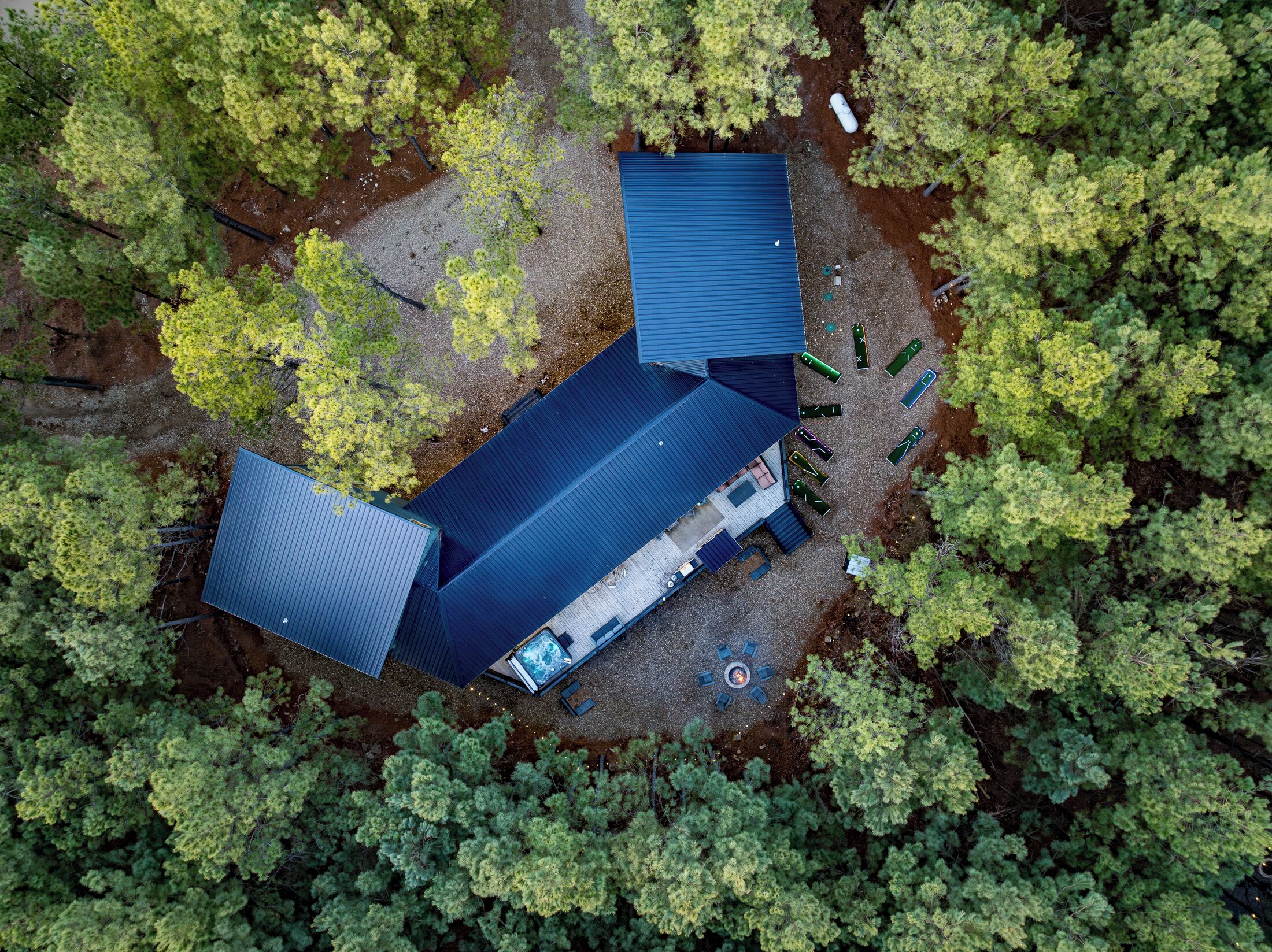 Eine Luftaufnahme einer Hütte mit blauem Dach, umgeben von dichtem Wald.