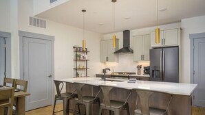 A modern kitchen with a central island, bar stools, and stainless steel appliances.