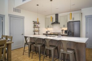 A modern kitchen with a central island, bar stools, and stainless steel appliances.