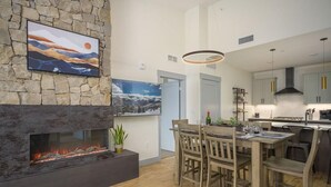 A modern kitchen with a stone fireplace, dining area, and kitchen island.