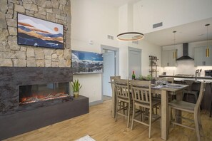 A modern kitchen with a stone fireplace, dining area, and kitchen island.