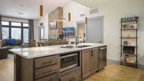 A modern kitchen with a large island, built-in appliances, and pendant lighting.