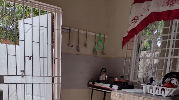 Una cocina con suelo de baldosas, estufa, fregadero y un armario.