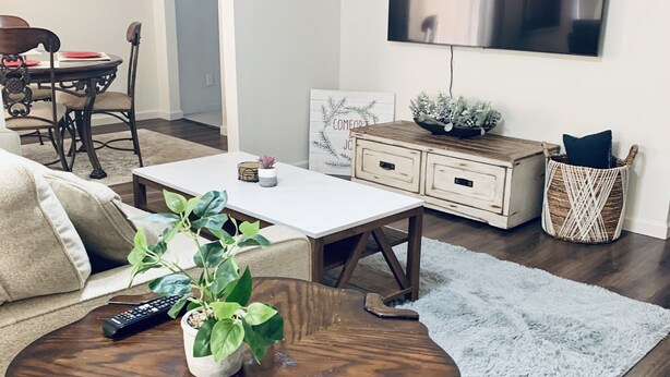 Un soggiorno moderno con un tavolino rotondo in legno, un divano, una TV a parete e un'area pranzo con tavolo e sedie.