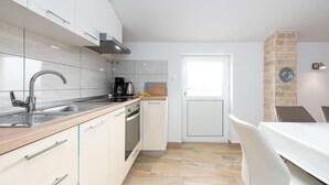 A modern kitchen with a sink, stove, and coffee maker. There is a door leading to a dining area with a table and chairs. - Gorgeous apartment in Vrsi with WiFi (Vrsi)
