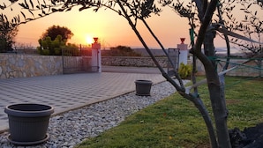 A patio area with a checkered tile floor, two planters, a stone wall, and a view of the sunset. - Gorgeous apartment in Vrsi with WiFi (Vrsi)