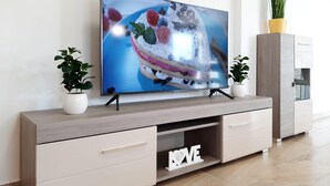 A modern living room with a flat-screen TV on a wooden TV stand, two potted plants, a white cabinet, and a decorative 'LOVE' sign. - Gorgeous apartment in Vrsi with WiFi (Vrsi)