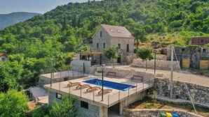 Una casa in pietra con piscina, immersa nel verde e circondata da dolci colline.