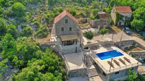 Una villa in pietra con piscina, immersa nel verde e in un paesaggio roccioso.