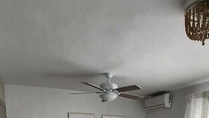 Ein geräumiges Wohnzimmer mit einer Couch, einem Couchtisch und einem Deckenventilator.