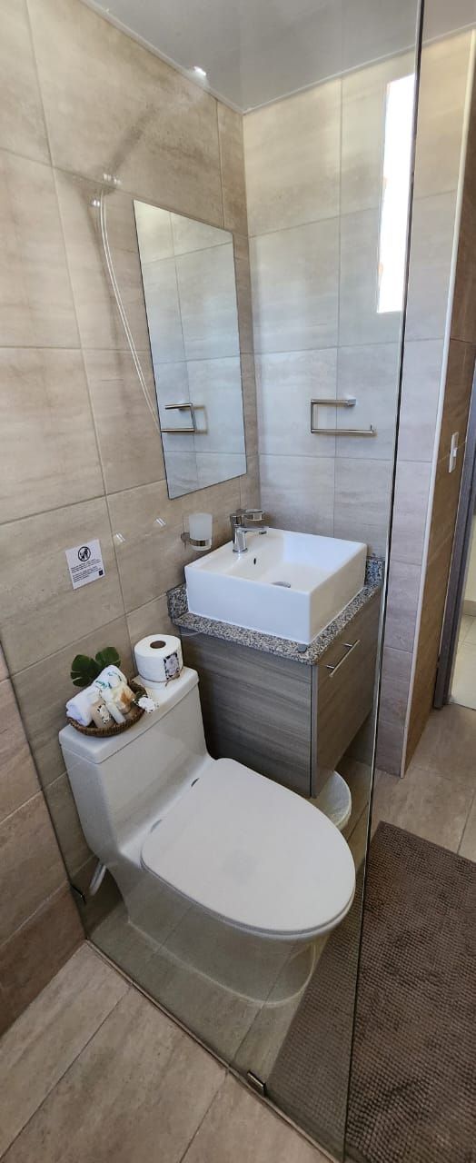 Un baño moderno con inodoro, lavamanos y espejo.