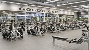 Ein gut ausgestattetes Fitnessstudio mit verschiedenen Trainingsgeräten, Bänken und einer Spiegelwand.