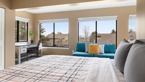 A bedroom with a large bed, a desk, and a sofa.