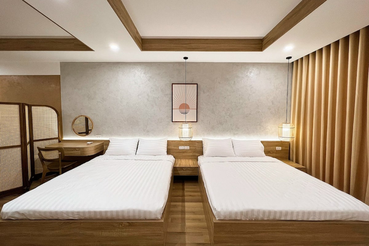 A modern hotel room with two beds, a desk, and a chair.