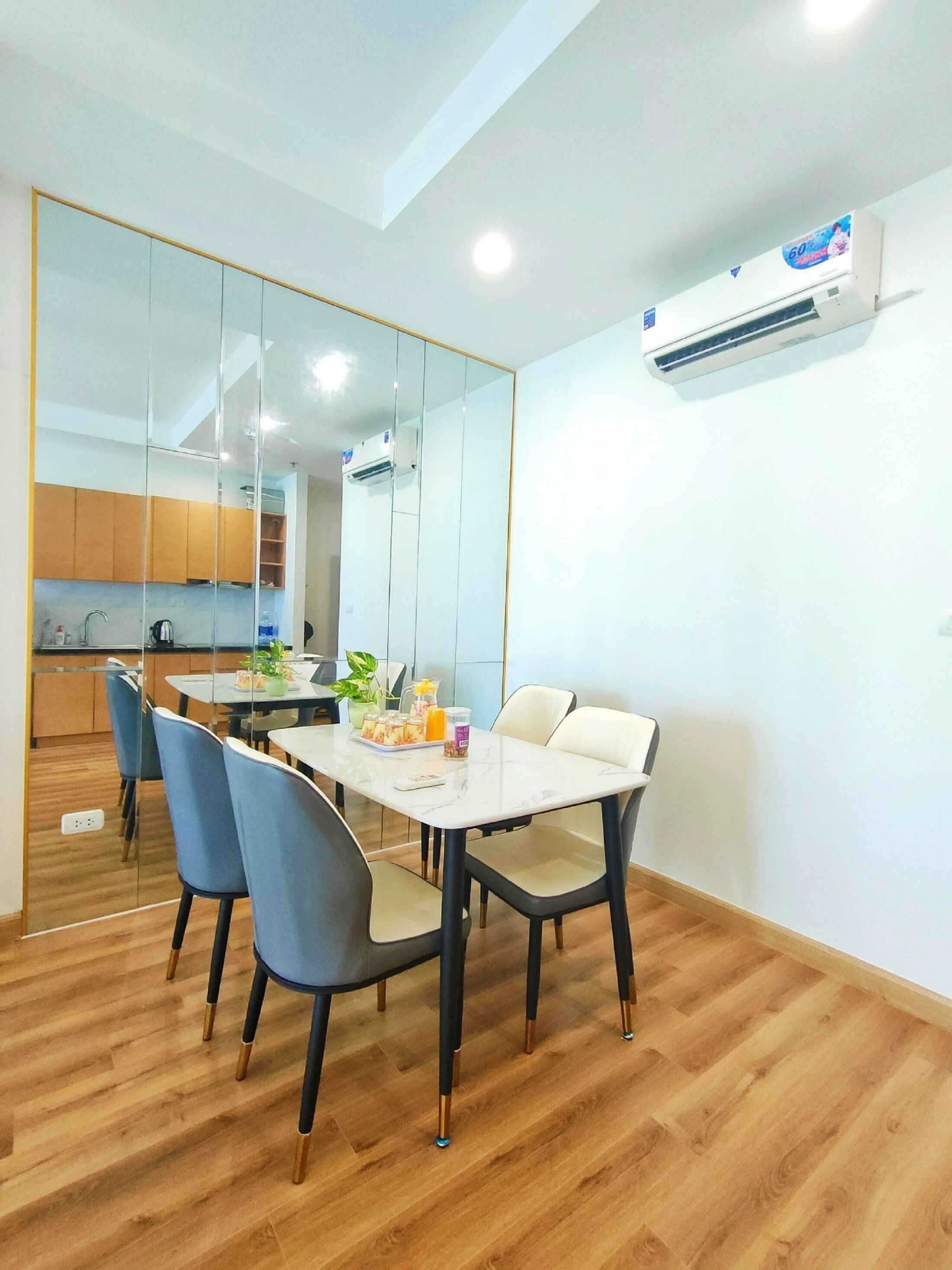 A modern dining area with a white table, four chairs, and a kitchen in the background.