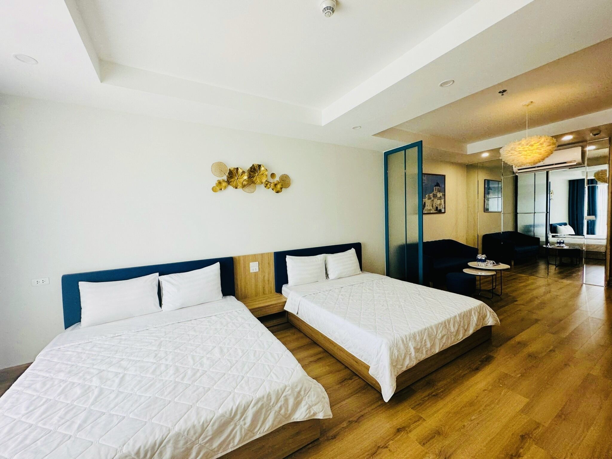 Una habitación de hotel con dos camas, un espejo grande, un sofá y una pequeña mesa.