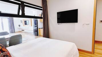 Habitación de hotel con una cama grande, un televisor de pantalla plana montado en la pared y vistas al exterior a través de un ventanal.