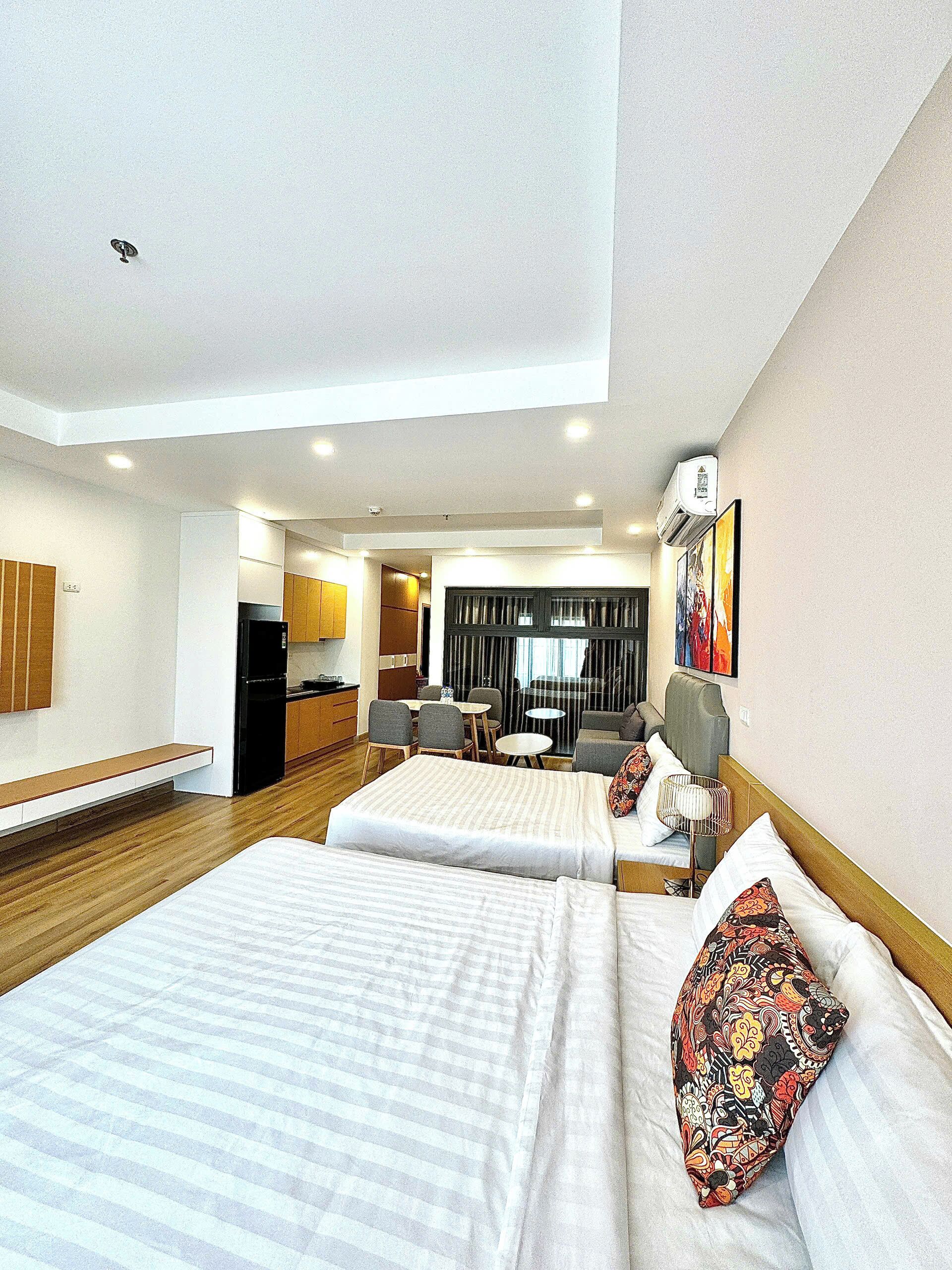 Une chambre d’hôtel avec deux lits, une kitchenette, un coin repas et une grande fenêtre.