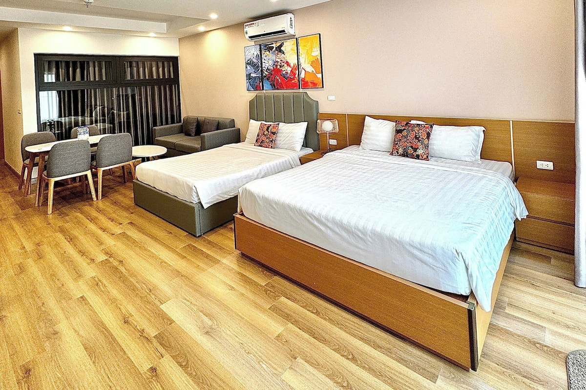 A hotel room with a large bed, a sofa, a desk, and a chair.
