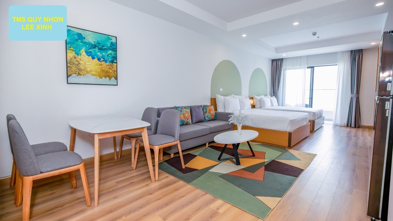 A modern hotel room with a bed, sofa, dining table, and chairs.