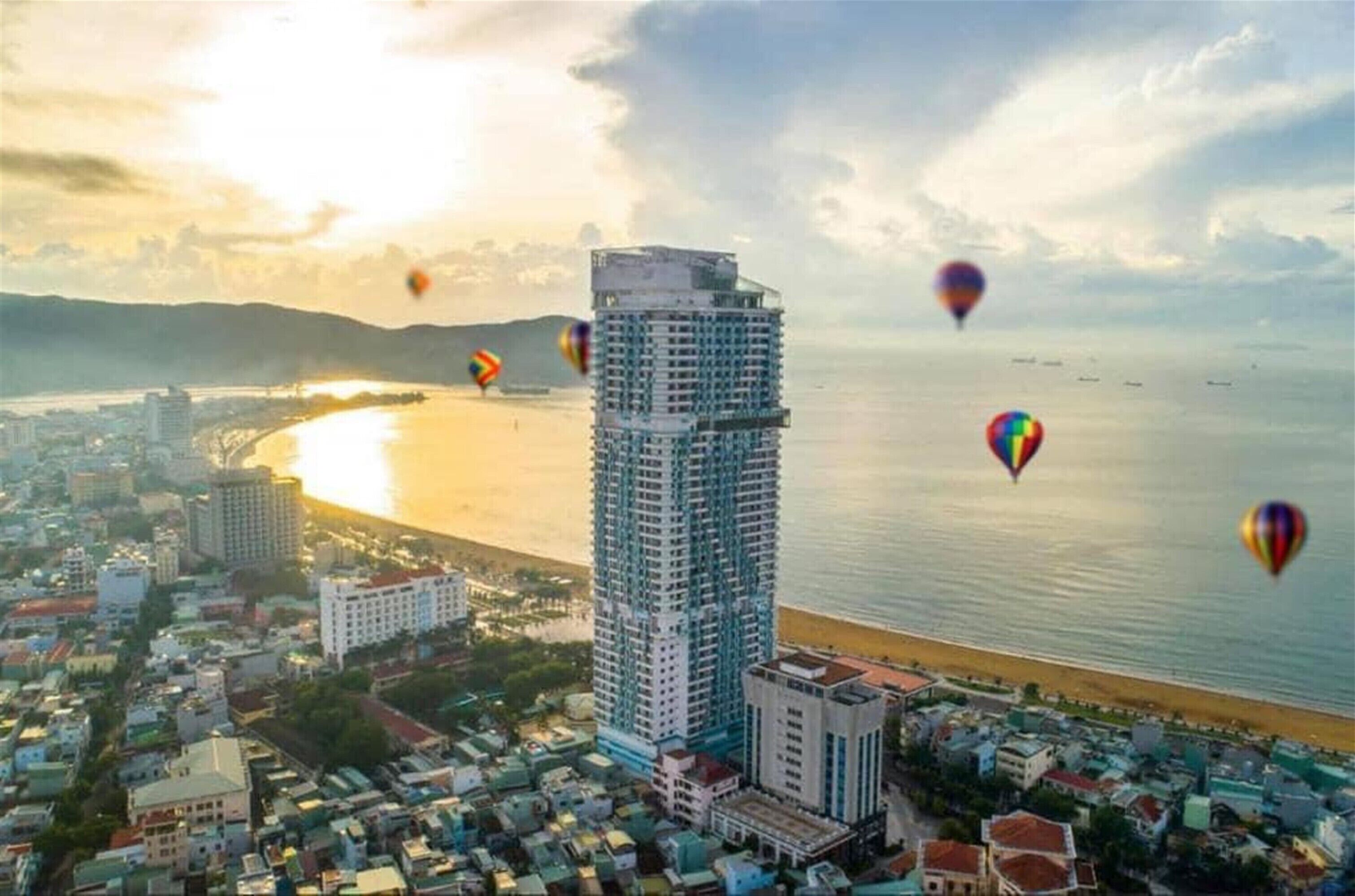 A high-rise building with a view of a coastal cityscape and the ocean.