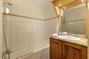 A bathroom with a bathtub, a sink, and a mirror. - V Balme 01: Beside Ski Lift; Pool, Sauna & Gym, Vallorcine (Argentiere), France (Vallorcine (Argentiere))