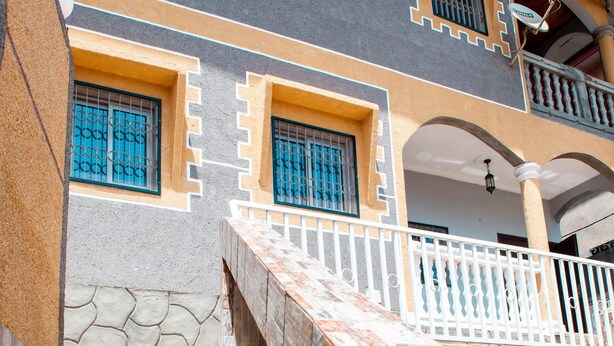A staircase leading to a building with a stone wall and a balcony with a railing. - Odza, modern apartment, 3 bedrooms, private parking (Yaoundé)