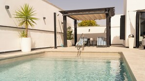 Een zwembad met ligbedden en een pergola.