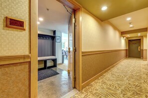 A hotel corridor with a bench, a coat rack, and a door leading to a room. - Le Chamois 504 - Upper Village (Whistler)