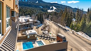 Et hotel med tagpool, udsigt til en skibakke og et bjerglandskab i baggrunden.
