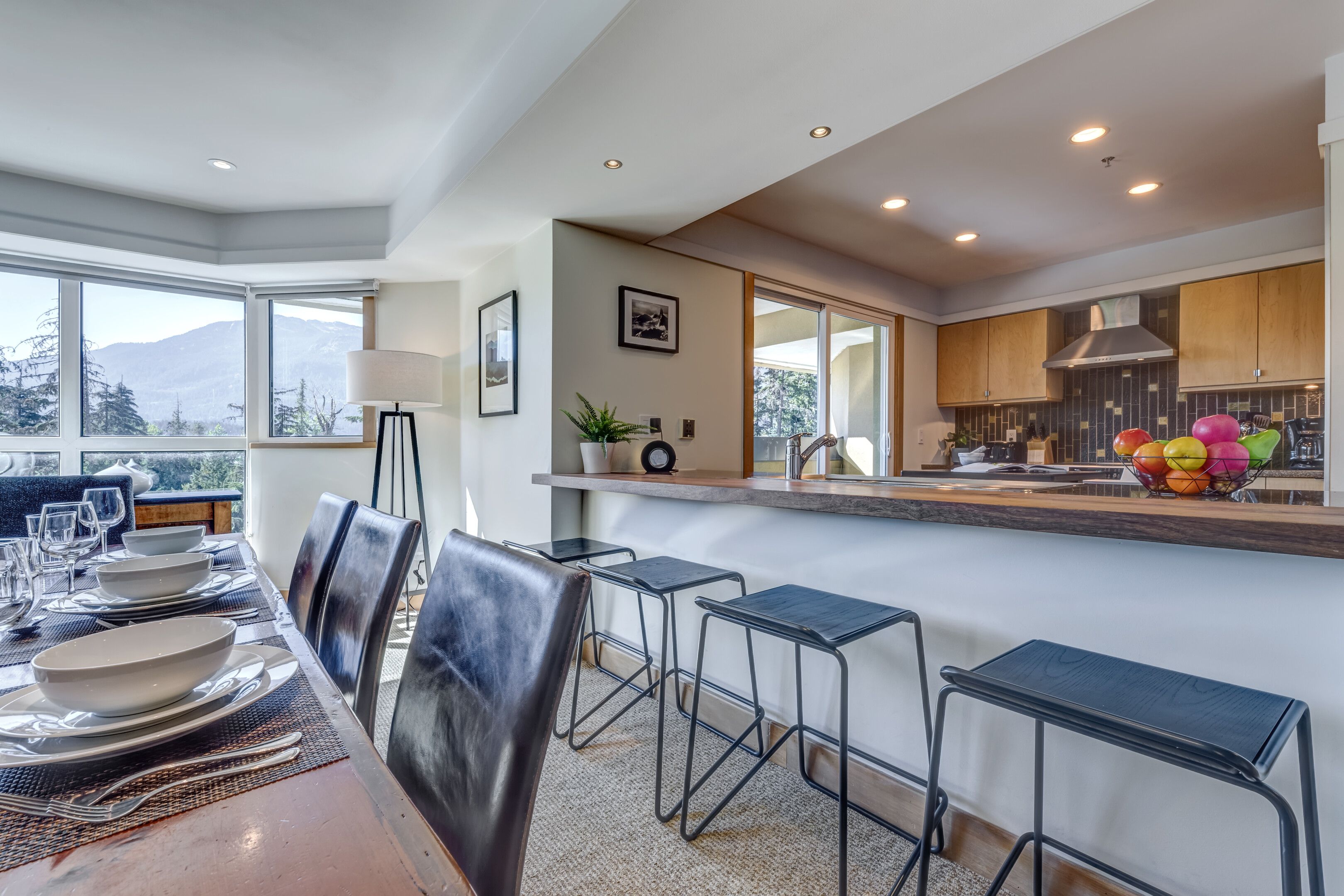 Un comedor moderno con una mesa larga, sillas y una cocina al fondo.