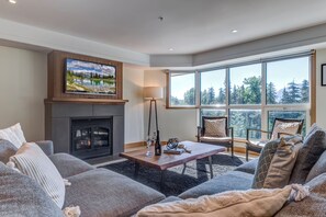 Relax by the fireplace in this inviting living room with a forest view.