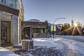 A hotel with a stone facade, a signboard, and a view of a snowy mountain.