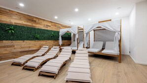 Quarto com piso de madeira, parede verde e várias camas com dosséis brancos.