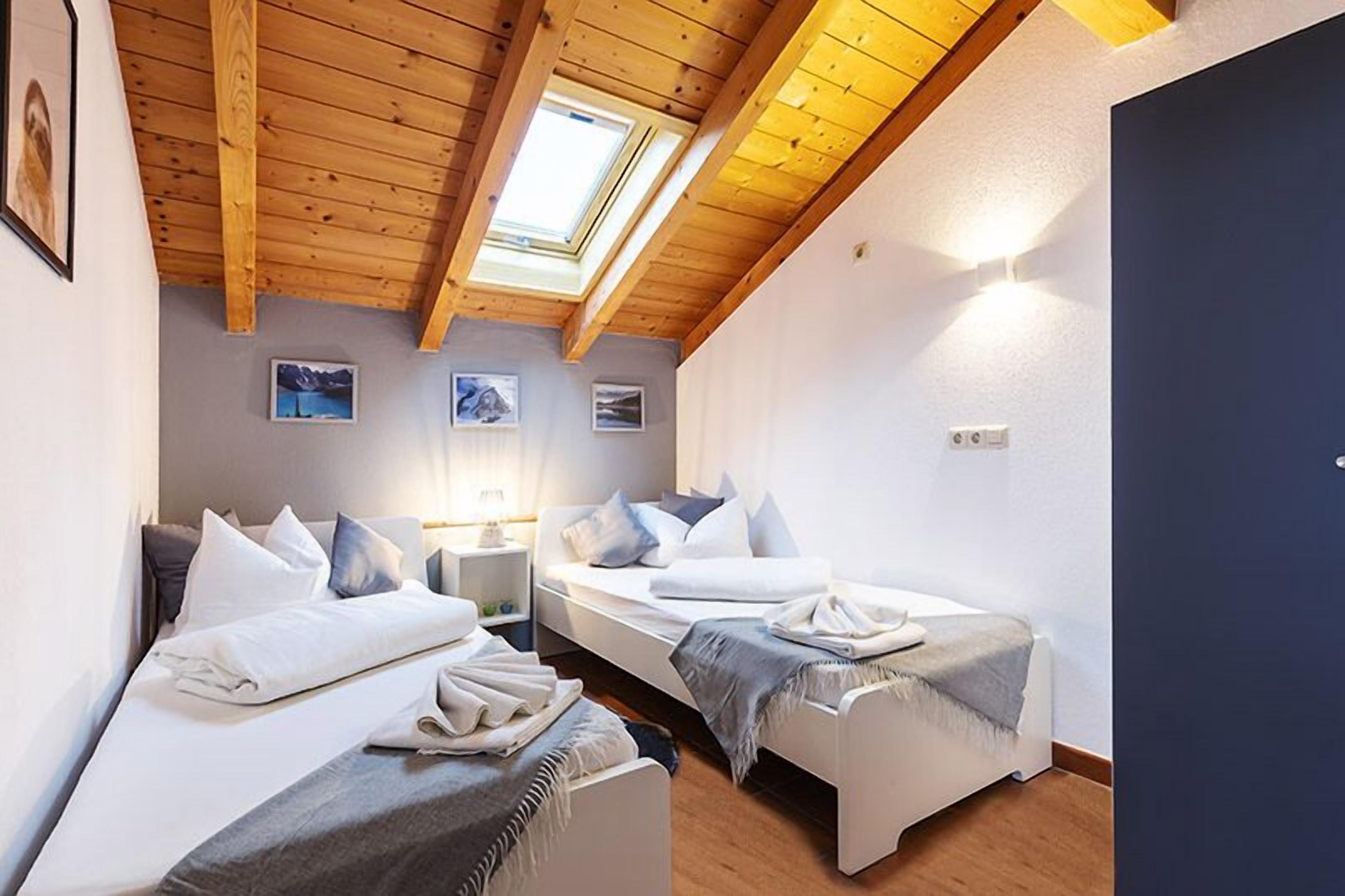 A hotel room with two beds, a skylight, and a view of the mountains.