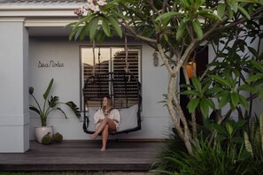 A person sitting on a hanging chair outside a building with a sign 'Dea Notes' on the wall. - Sea Notes Beach House Yamba (Yamba)