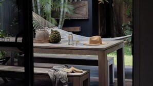 A wooden table with a woven hat, a pineapple, a glass bottle, and a book. - Sea Notes Beach House Yamba (Yamba)